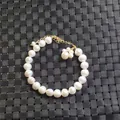 Elegant freshwater pearl bracelet with golden flower charm on black textured background - Bracelet