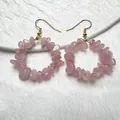 Primo piano di orecchini a cerchio in quarzo rosa con ganci dorati su piatto bianco - Quarzo rosa
