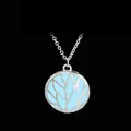 Detail of life tree hollow pendant necklace glowing in light blue on black background - Blue