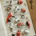 Flache Darstellung von 14 handgemachten Tieranhängern aus Keramik auf Vintage-Buchseiten - Hirsch