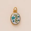 Gedetailleerde close-up van ovale emaille hanger met Love-tekst en blauwe bloemen - Liefdesbrief Bloemenstijl