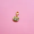 Detail of golden cat pendant with white enamel inlay and lobster clasp on pink background - Kitten Pendant
