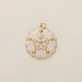 Detailed view of a gold floral charm with white enamel and sparkling center zircons - White Zircon Flower Style