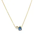 Macro view of gold teardrop necklace featuring blue zircon gemstone and round white pearl - September