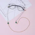 Detail of eyewear chain with green clover charms, white pearls and gold metal links - Green