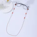 Detail of gold eyewear chain with red butterfly charms and white pearls on black glasses - Butterfly Red
