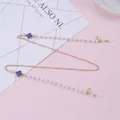 Detail of clover eyewear chain with purple charms and white pearls on pink background - Blue