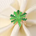 Dettaglio portatovagliolo dorato con smalto verde su tovagliolo color crema - Forma di Foglia di Fiocco