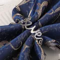 Macro view of silver metal Love napkin ring with heart detail on blue jacquard fabric - Silver