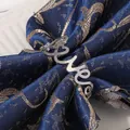 Polished silver metal napkin ring with cursive Love design on a deep blue silk napkin - Silver
