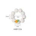 Wooden bead napkin ring with 9 white beads, one sunflower bead, and twine tassel details - Z1223