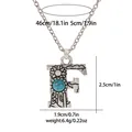 Detail of vintage silver letter F necklace showing sunflower relief and turquoise stone - A3217-F