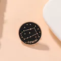 Macro d'un pin's Gémeaux en émail noir avec étoiles dorées et texte Gemini - Gémeaux