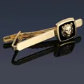 Macro shot of gold-plated tie clip with embossed lion head on blue mirror background - Gold Lion Head Tie Clip