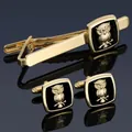 Golden tie clip and cufflinks set with black square inlay and owl relief on blue background - Gold Owl Set