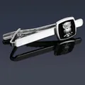 Close-up of silver owl tie clip with black square inlay on blue reflective background - Silver Owl Tie Clip