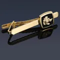 Macro shot of gold tie clip with black enamel wolf head emblem on reflective surface - Gold Wolf Tie Clip