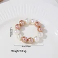 Detail view of U-shaped champagne gold napkin ring with pearls on a white ceramic plate - Two-Tone Style (Z1149-1) / White Champagne Gold Mix