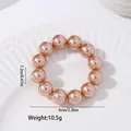 Detailed view of U-shaped napkin ring with warm rose gold pearls on a ceramic dish - Solid Color Metallic Style (Z1149-3) / Champagne Gold Metallic