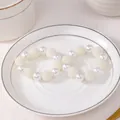 Primer plano de servilleteros en forma de U oro champán con perlas blancas en plato - Estilo Bola de Perlas Texturizada (Z1168)