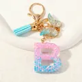 Glitter resin letter B keychain with pink-blue gradient, blue tassel and gold butterfly - Letter B (D1417-B)