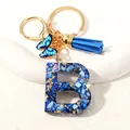 Letter B initial keychain with blue resin, gold foil, butterfly, and tassel charm - Letter B (D1413-B)