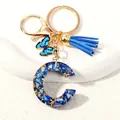 Detail of blue resin letter C keychain with gold foil, blue tassel and butterfly charm - Letter C (D1413-C)