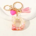 Detailed view of pink resin letter D keychain with gold foil, tassel and heart charm - Style D(D1416-D)
