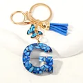 Letter G resin keychain with blue stones, gold flakes, butterfly and blue tassel - Letter G (D1413-G)