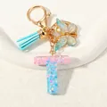 Light blue letter T keychain with glitter, butterfly charm and silk tassel details - Letter T (D1417-T)