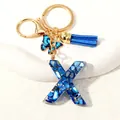 Golden keychain with letter X in blue resin marble, suede tassel, and butterfly charm - Letter X (D1413-X)