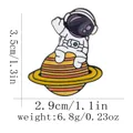 Detailansicht der Cartoon Astronaut Emaille-Anstecknadel Maße: 3,5 cm Höhe und 2,9 cm Breite - Astronaut sitzt auf dem Saturn (C3075-4)