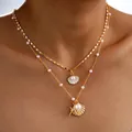 Detalle de un collar dorado de varias capas con colgantes de estrella de mar y concha - 6508401hb