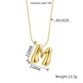 Macro detail of 18K gold plated stainless steel letter M puffy bubble pendant necklace - Letter M