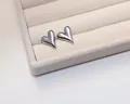 Macro shot of silver heart stud earrings with a high-polish finish on velvet display - Stud Earrings / Silver