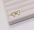 Macro shot of polished gold heart stud earrings on a cream velvet jewelry tray - Stud Earrings / Gold