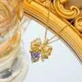 Macro shot of gold bow pendant with pavé zircon and purple heart-shaped stone - Necklace / Gold