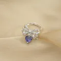 Macro shot of silver bow ring with heart purple gemstone and micro-pave crystals - Ring / Silver