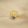 Macro detail of golden bow ring with white zircon pave and purple heart gemstone - Ring / Gold