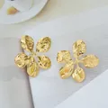 Détail de grandes boucles d'oreilles fleur dorées avec finition martelée sur papier - Style de Fleur (C670)