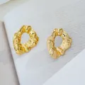Détail macro de boucles d'oreilles dorées à texture lave et éclat métallique poli - Rond Irrégulier (C670)