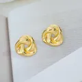 Vue détaillée des boucles d'oreilles triangulaires torsadées dorées sur fond de magazine - Triangle Creux (C670)
