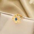 Dettaglio macro dell'anello a fiore dorato con zaffiro blu e petali di zirconi - Anello Dorato