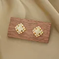 Elegant gold clover earrings with white zircon center and pearl rim on silk background - Gold Earrings