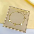 Macro des pendentifs gourde dorés avec incrustations de nacre sur une chaîne fine - Bracelet Wulu Blanc Doré