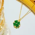 Macro detail of a gold clover necklace with green heart-shaped gemstones and zircon accents - Gold Green