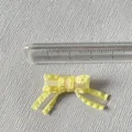Vista macro che mostra la dimensione del mini fiocco in organza gialla per fai da te - Giallo
