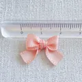 Macro shot of a 2cm pink satin ribbon bow accessory with ruler for size measurement - Pink