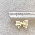 Close-up of a 1.5cm cream mesh bow accessory with a ruler showing its small size and texture - Off White