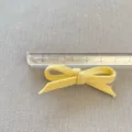 Dettaglio di un fiocco in tessuto giallo chiaro di 6 cm con righello per la misura - Stile Giallo Chiaro (4)